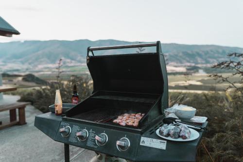 a grill with a plate of food and a bottle of wine at Chinamans Ridge on Chinamans Terrace - Bendigo, Tarras - Central Otago in Tarras