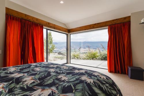 a bedroom with a bed and a large window at Chinamans Ridge on Chinamans Terrace - Bendigo, Tarras - Central Otago in Tarras