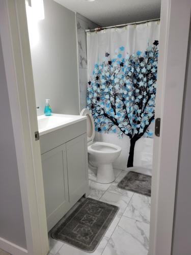 a bathroom with a toilet and a tree shower curtain at Brand New 2 Bedroom Basement Suite with Wifi in Edmonton