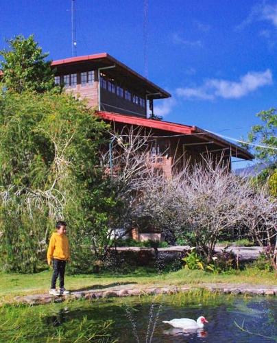 a person standing in front of a house with a pond at Los Quetzales Ecolodge & Spa in Cerro Punta