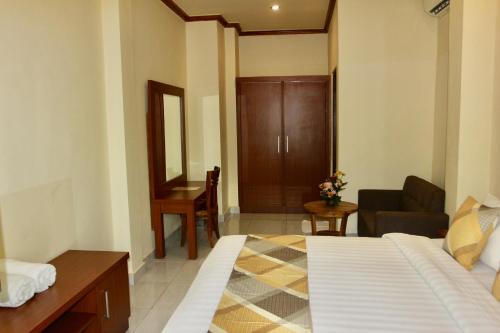 a room with a bed and a desk and a chair at Guesthouse Gusti Putu Oka in Ubud