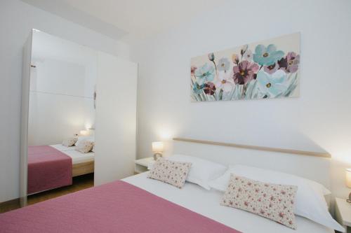 Un dormitorio con una cama rosa y blanca y un espejo en Apartments Civadelić, en Trogir