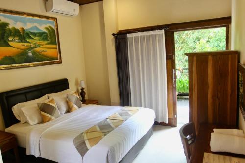 a bedroom with a bed and a large window at Guesthouse Gusti Putu Oka in Ubud