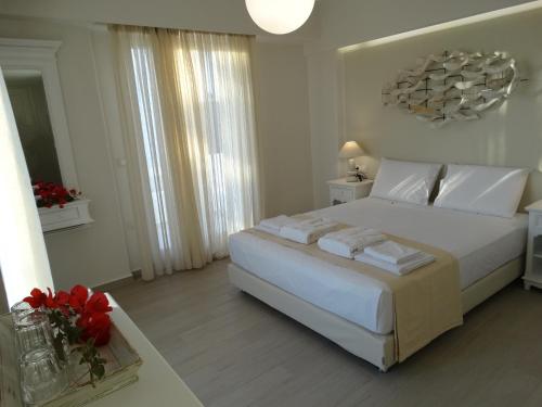 a white bedroom with a large bed with white pillows at Anassa Suites in Naxos Chora