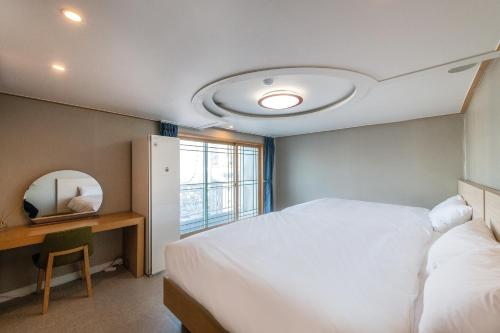 a bedroom with a bed and a table and a mirror at Sokcho Good Morning Hotel and Resort in Sokcho