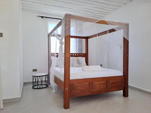a bedroom with a canopy bed with white sheets at Cave Diani Holiday Apartments in Diani Beach
