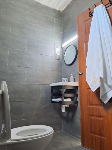 a bathroom with a toilet and a sink and a mirror at Cave Diani Holiday Apartments in Diani Beach