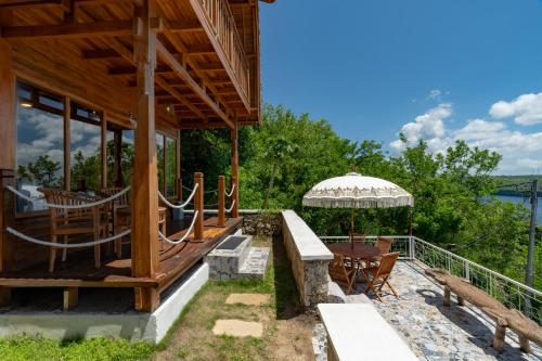 a house with a deck with a table and chairs at Butterfly Villas Nusa Ceningan in Nusa Lembongan