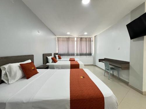 een hotelkamer met 2 bedden en een bureau bij HOTEL MAGIC in Piura