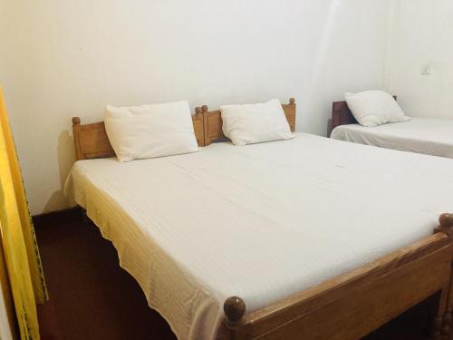 two beds in a room with white sheets and pillows at Nugasewana Guest in Anuradhapura