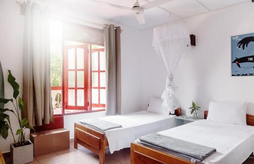 a bedroom with two beds and a window at Neutral Wind Beach Home in Matara