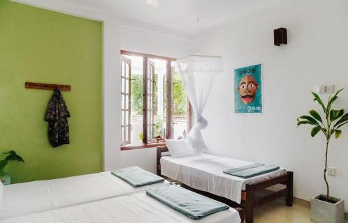 two beds in a room with green and white at Neutral Wind Beach Home in Matara