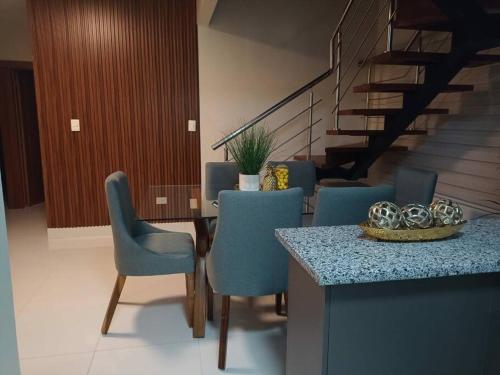 a dining room with blue chairs and a table and stairs at Estrella de luz penthouse a estrenar in Santiago de los Caballeros