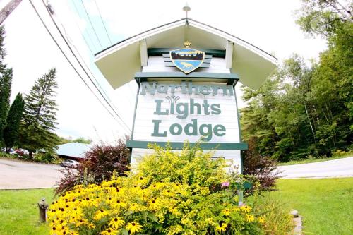 a sign for the north american lights lodge with flowers at Northern Lights Lodge in Stowe