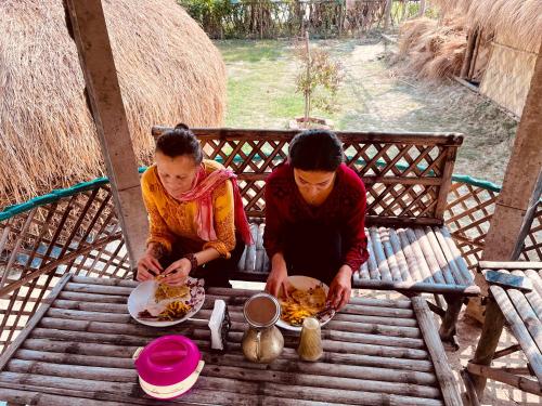 dos personas sentadas en una mesa comiendo comida en Satrangi Homestay Sundarban en Kākdwīp
