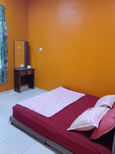 a bed in a room with an orange wall at Pelangi Homestay 2 in Bachok