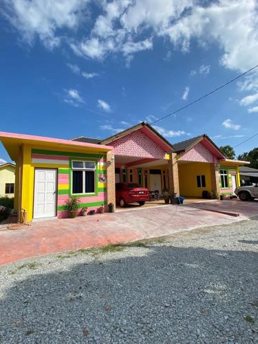 une maison colorée avec une voiture garée devant elle dans l'établissement Pelangi Homestay 2, à Bachok