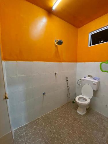 La salle de bains est pourvue de toilettes et d'un mur orange. dans l'établissement Pelangi Homestay 2, à Bachok