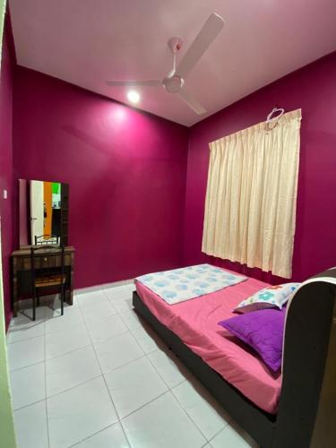 a bedroom with a purple wall with a bed and a desk at Pelangi Homestay 2 in Bachok