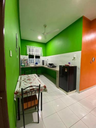 a kitchen with green walls and a table with a chair at Pelangi Homestay 2 in Bachok