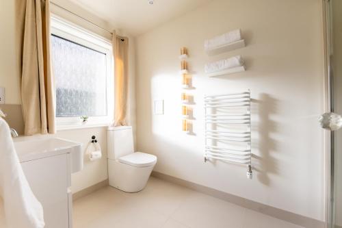 uma casa de banho branca com um WC e uma janela em The Koko Rooms em Inverness