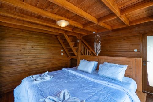 a bedroom with a blue bed in a wooden room at Butterfly Villas Nusa Ceningan in Nusa Lembongan