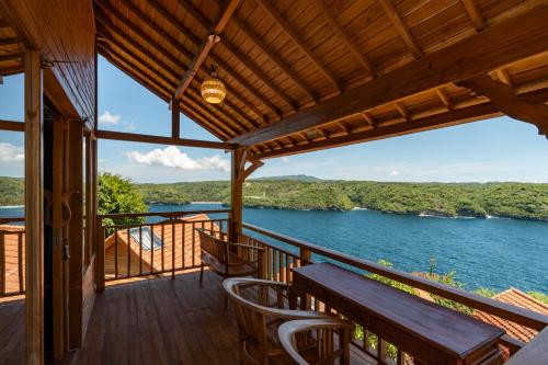 a porch with a table and chairs and a view of the water at Butterfly Villas Nusa Ceningan in Nusa Lembongan