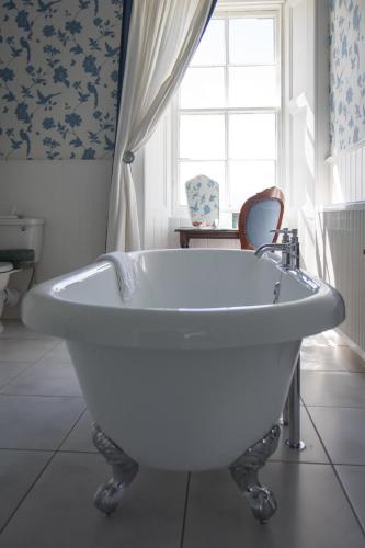 a white bath tub in a bathroom with a window at Whitehouse Country House in Saint Boswells