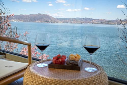 two glasses of wine and a plate of fruit on a table on a balcony at Dali Beauty Seaview B&B in Dali