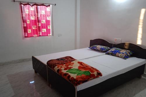 a bed sitting in a room with a window at OYO Shiv guru guest house in Bodh Gaya