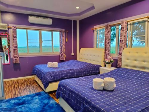 two beds in a room with purple walls and windows at อุดมทรัพย์วิลเลจฟาร์ม in Ban Huai Nam Khem