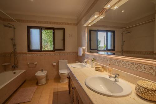 a bathroom with two sinks and a tub and a toilet at Villa Cal Peso in Port de Pollensa