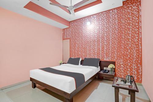 - une chambre avec un lit et un mur rouge dans l'établissement Collection O Hotel Raj Palace, à Sātej