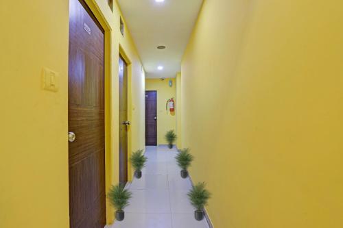 un couloir avec des murs jaunes et des plantes en pot au sol dans l'établissement Collection O Hotel Raj Palace, à Sātej