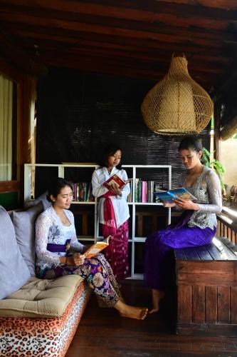 drie vrouwen zitten in een kamer boeken te lezen bij Umajero Hut in Silebeng