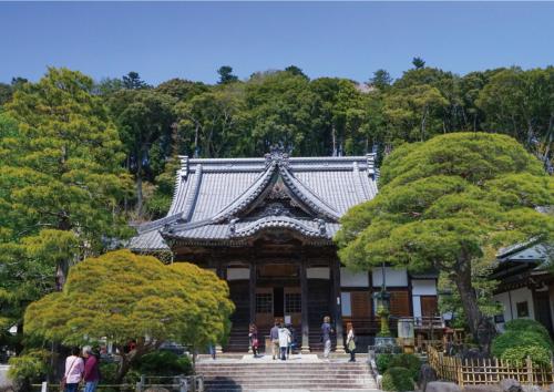 an asian style building with trees in front of it at Hostel Knot in Izu