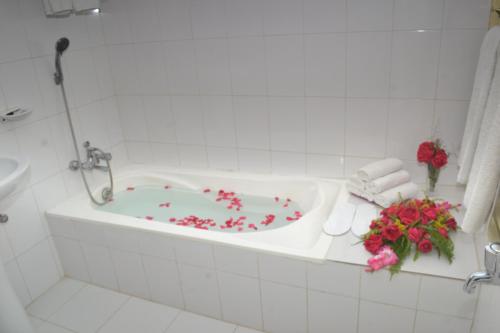 a white bathroom with a tub with flowers in it at Hotel Lighthouse Family Retreat in Cox's Bazar