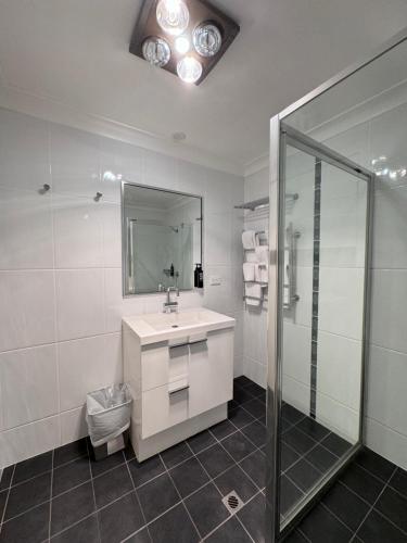 y baño blanco con lavabo y ducha. en ibis Styles Broken Hill, en Broken Hill