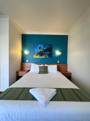 1 dormitorio con 1 cama grande y pared azul en ibis Styles Broken Hill, en Broken Hill