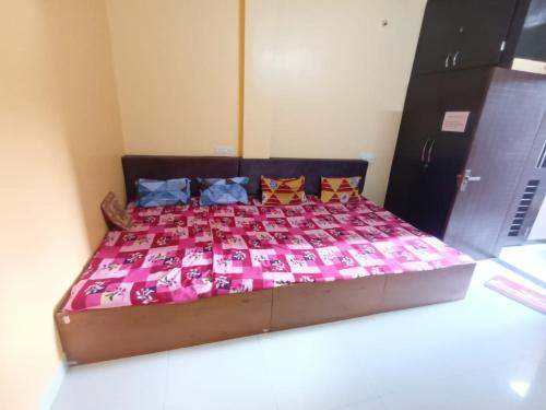 een bed in een kamer met een roze dekbed en kussens bij Anand Yatri Grah, Ujjain in Ujjain