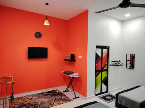 a living room with an orange wall with a television at Roomstay Kak Ton in Kuala Terengganu