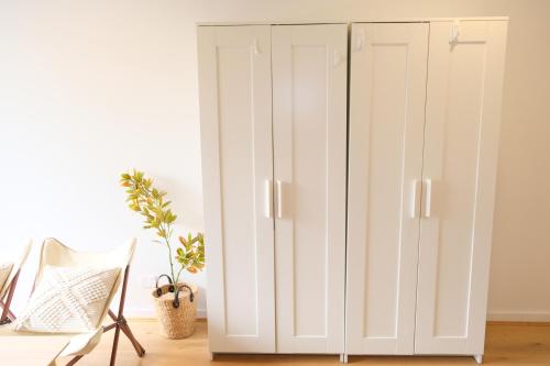 a white wardrobe in a room with a chair at CBD Japanese Retreat 2BR 1P Brekky Wifi Netflix in Canberra
