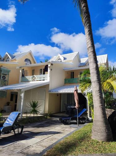 a house with a palm tree and two chairs at 23 Residence Thalassa, in Belle Mare