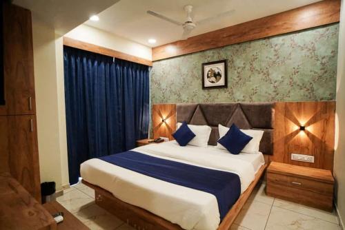 a bedroom with a large bed with blue pillows at Hotel Mahaveer in Ahmedabad