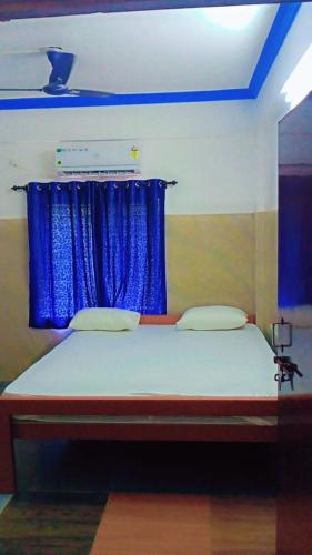a bedroom with a bed with a blue curtain at V K HOLIDAY HOMEs in Malpe