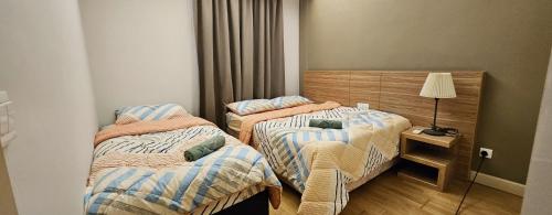 2 camas en una habitación pequeña con lámpara en Royal Suite, en Kuala Lumpur
