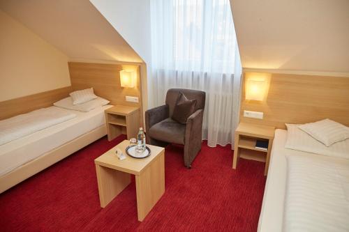 a hotel room with two beds and a chair at Flair Hotel Weinstube Lochner in Bad Mergentheim