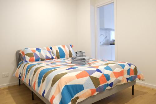 a bed with a colorful comforter in a room at CBD Japanese Retreat 2BR 1P Brekky Wifi Netflix in Canberra