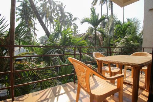 a table and chairs on a balcony with palm trees at Redstone Resort-Nagaon-Alibaug in Nagaon