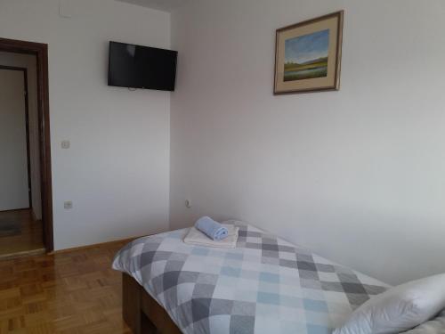a bedroom with a bed and a tv on a wall at Apartman kod dide i bake in Vukovar